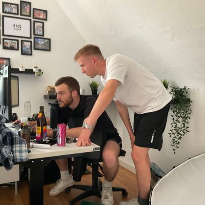 Florian und David im Büro der Anfangsjahre, vor der 116 Media Bilderwand
